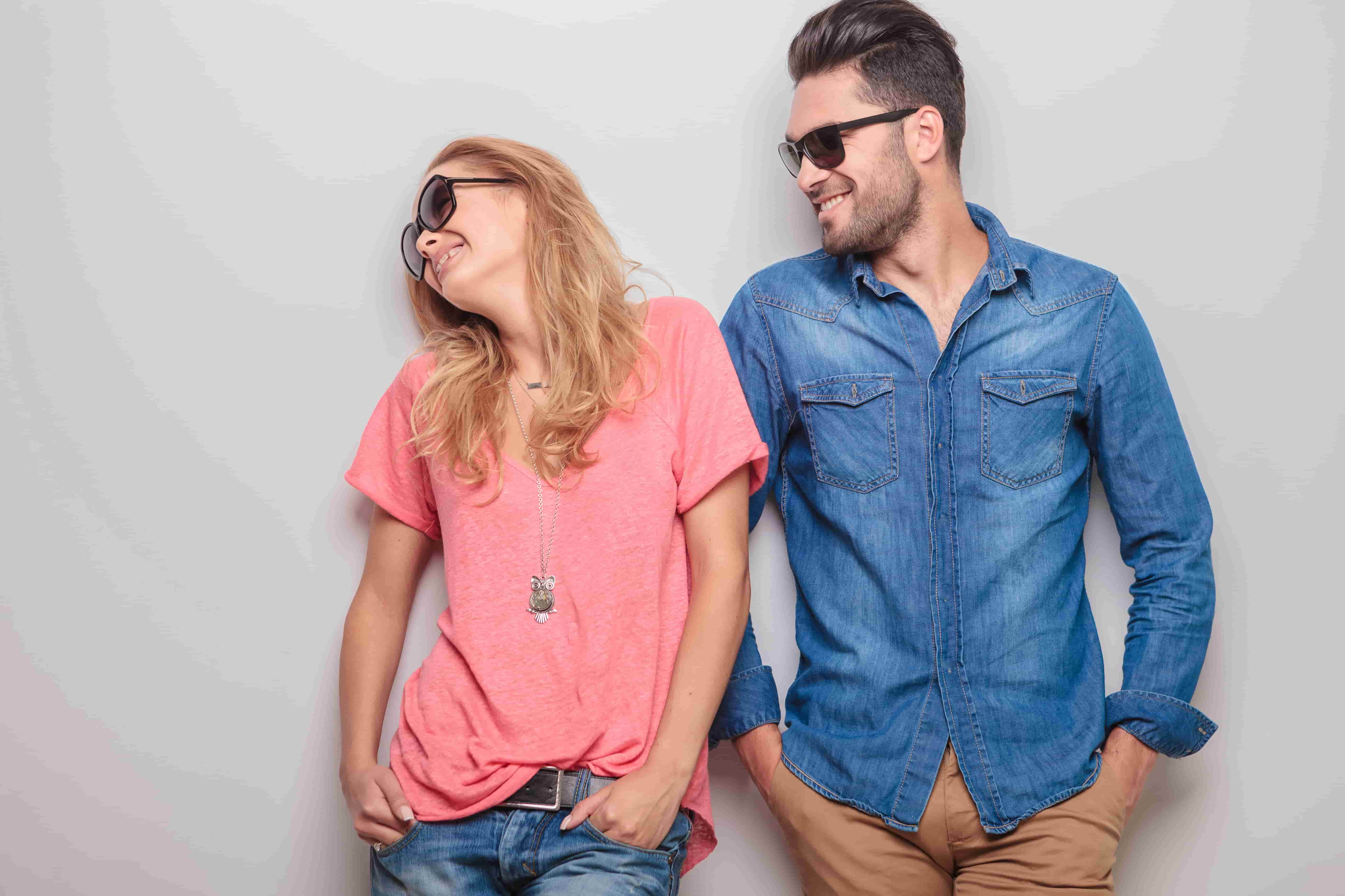 couple leaning against a wall with sunglasses on